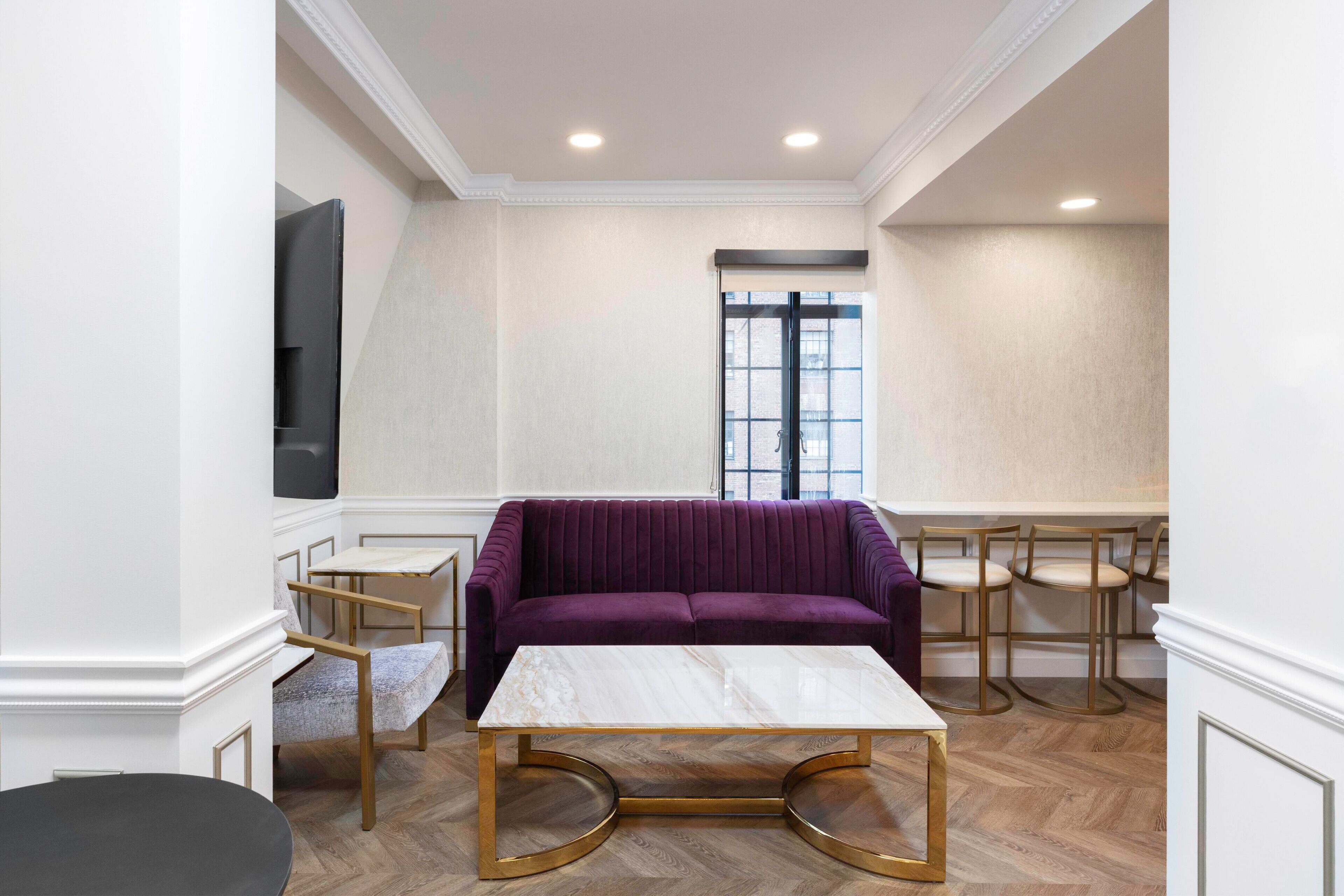 Uma sala de estar moderna com um sofá roxo, uma mesa de centro de mármore e uma janela grande.
