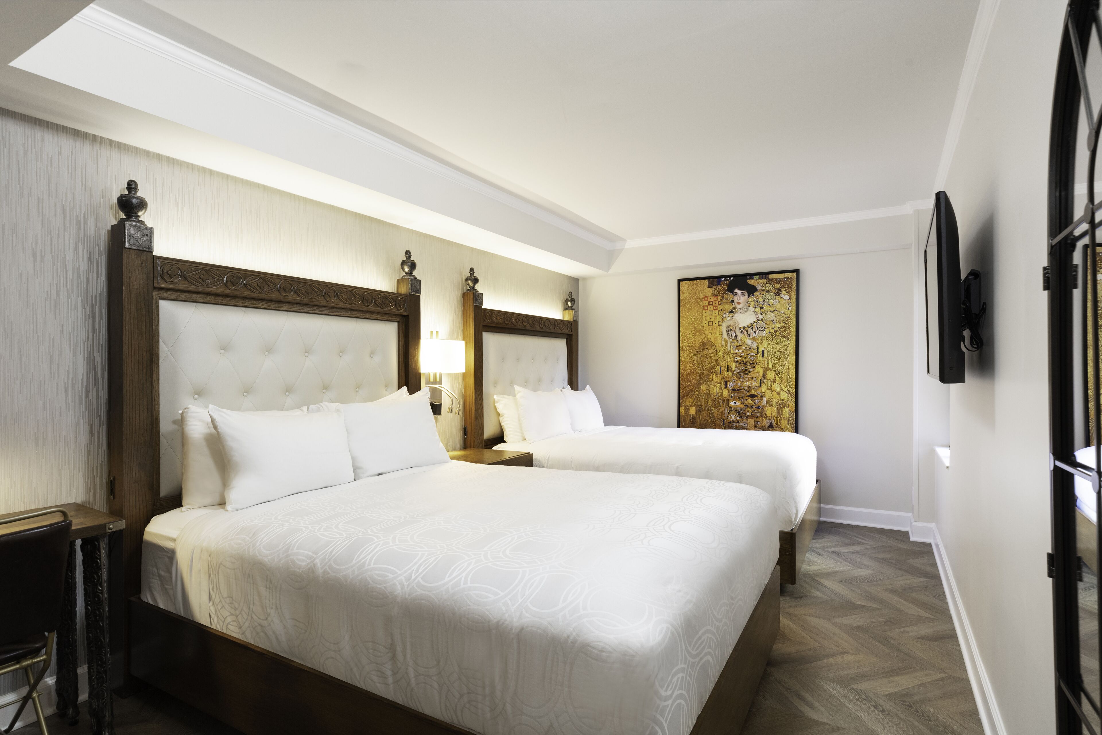 Una habitación de hotel con dos camas, un escritorio y un cuadro grande en la pared.