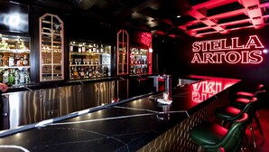 A bar area with a neon sign reading "STELLA ARTOIS" and a well-stocked liquor shelf. - Westgate New York Grand Central (New York)