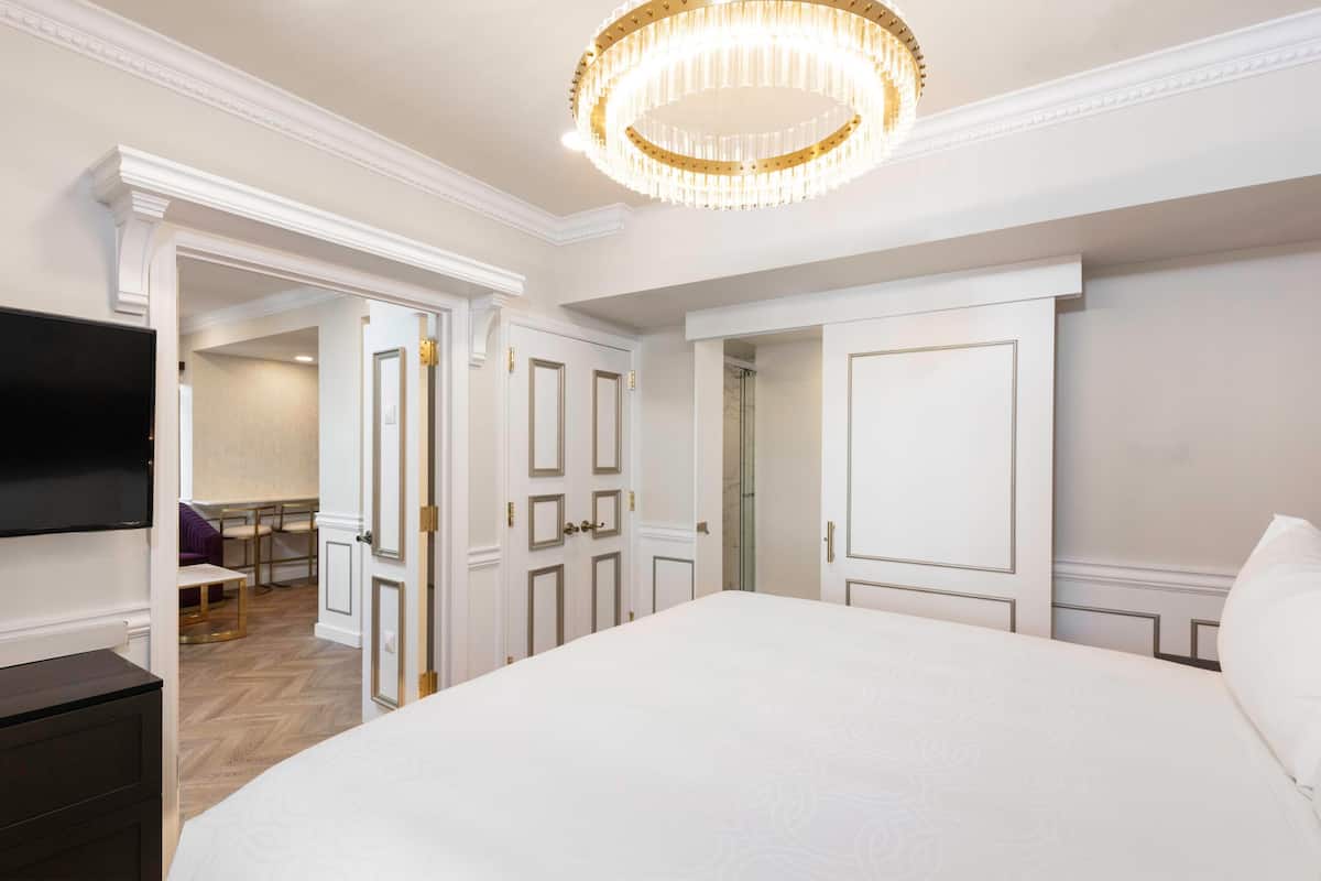 A bedroom with a large bed, a television, and a chandelier.