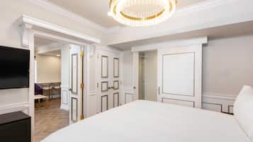 A bedroom with a large bed, a television, and a chandelier.