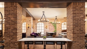 A restaurant with brick walls, large windows, and a central dining table with chairs. - Westgate New York Grand Central (New York)