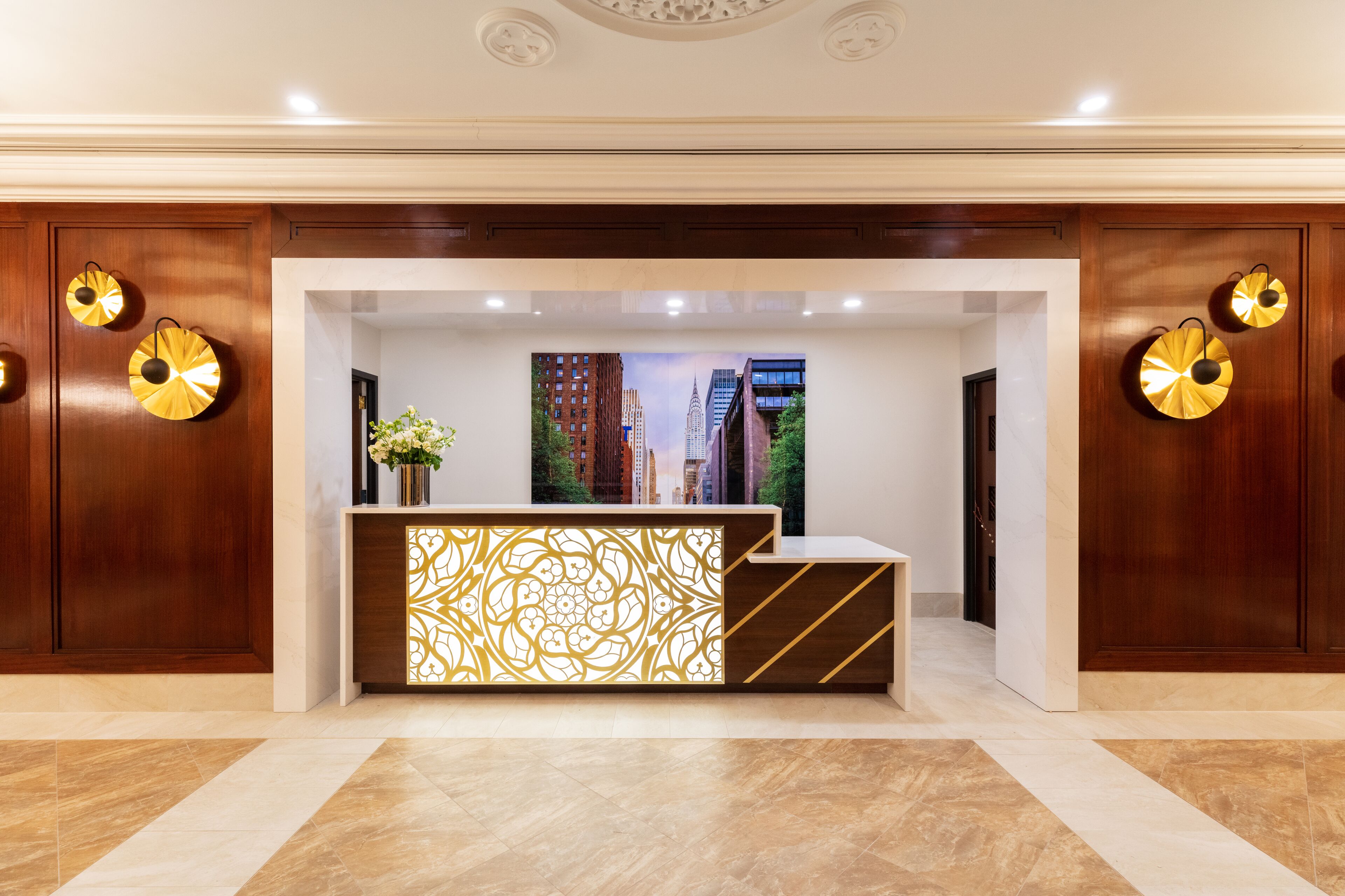 Zona de recepción con diseño moderno, que incluye un mostrador con un fondo estampado, paneles de madera y apliques decorativos.