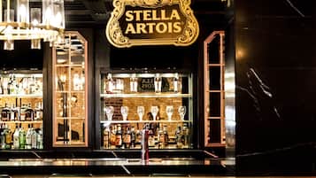 Un bar con un letrero que dice "Stella Artois" y una bicicleta roja estacionada adelante.