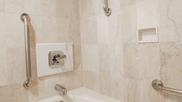 Un baño con bañera, barras de apoyo y cabezal de ducha.