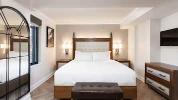 Una habitación de hotel con una cama grande, lámparas de noche, un televisor y un aparador de madera.