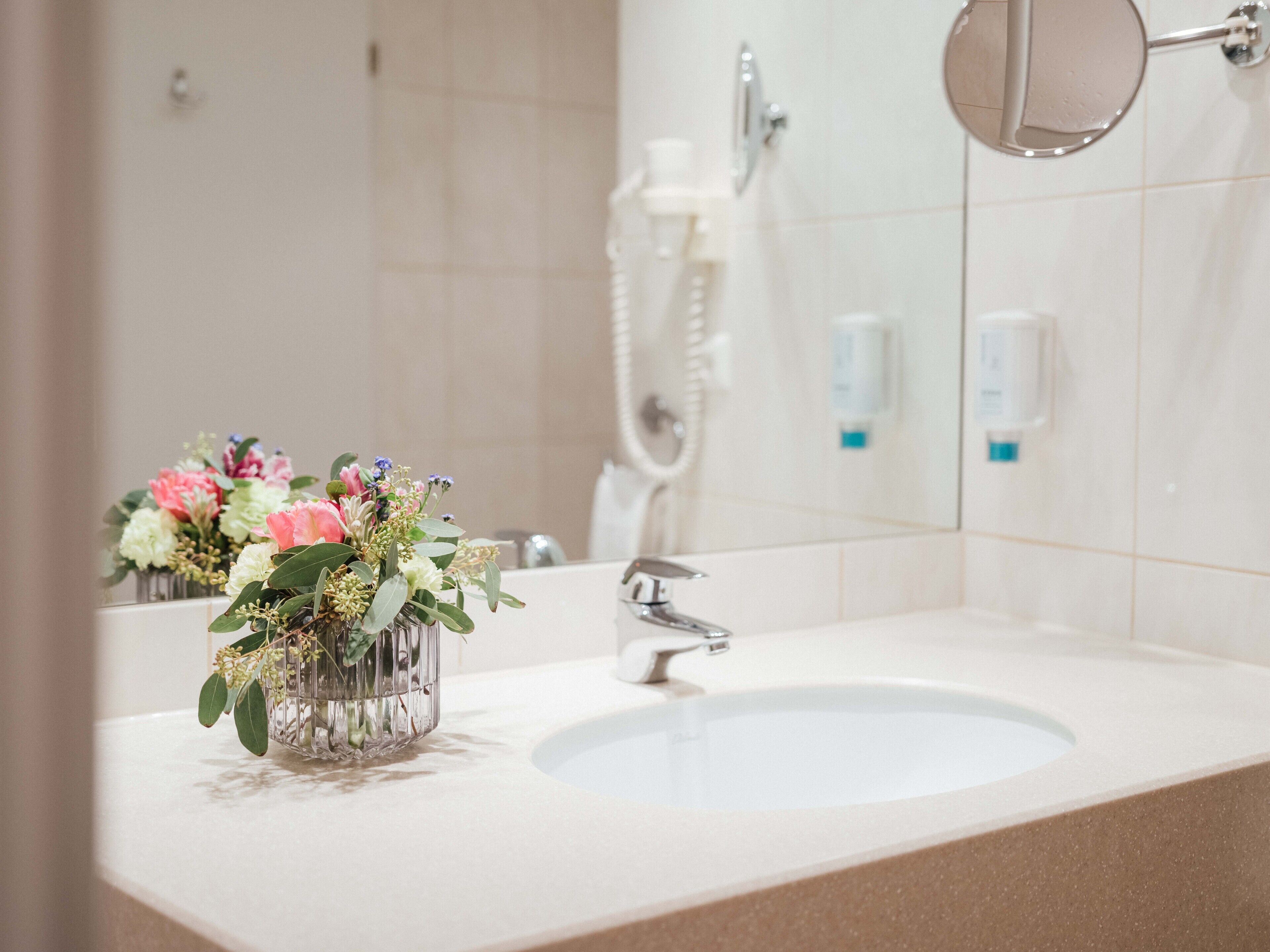 A bathroom with a sink, a mirror, and a shower.