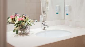 A bathroom with a sink, a mirror, and a shower.
