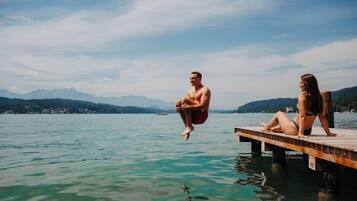 A wooden dock extending into a calm lake with mountains in the background.