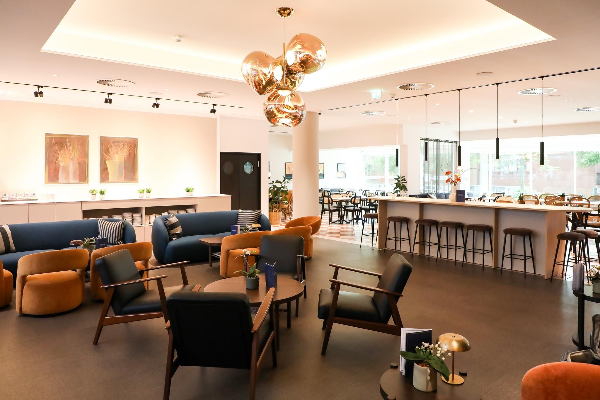 A modern interior with a bar area, seating arrangements, and a large window providing natural light.
