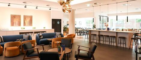 A modern interior with a bar area, seating arrangements, and a large window providing natural light.