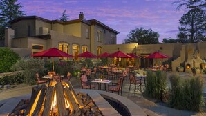 A patio area with outdoor seating, a fire feature, and a building in the background. - La Posada de Santa Fe, A Tribute Portfolio Resort & Spa by Marriott (Santa Fe)