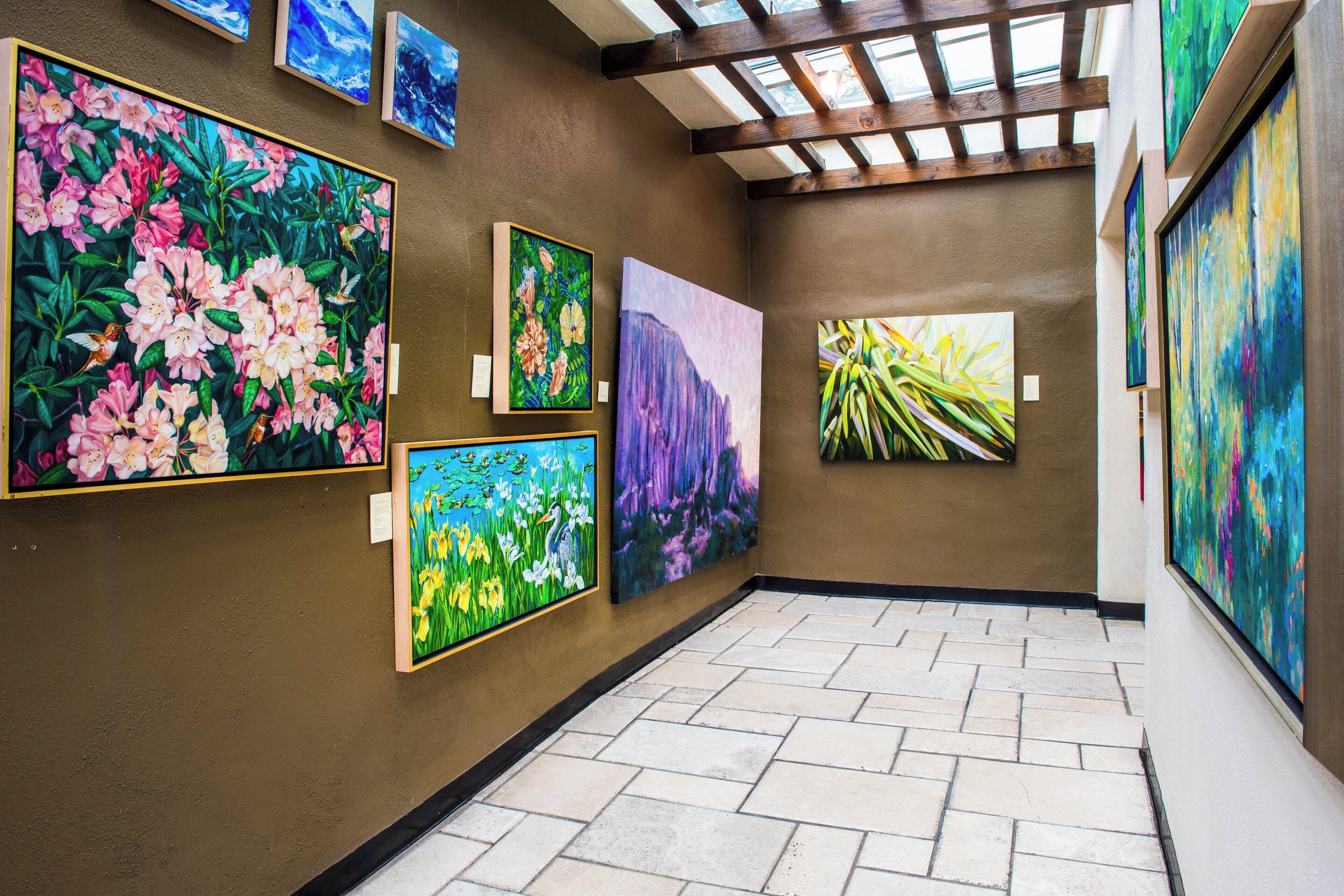 A hallway with a tiled floor and walls adorned with various paintings.