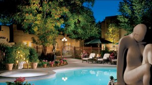 A poolside area with a statue, lounge chairs, and a small table with a candle. - La Posada de Santa Fe, A Tribute Portfolio Resort & Spa by Marriott (Santa Fe)