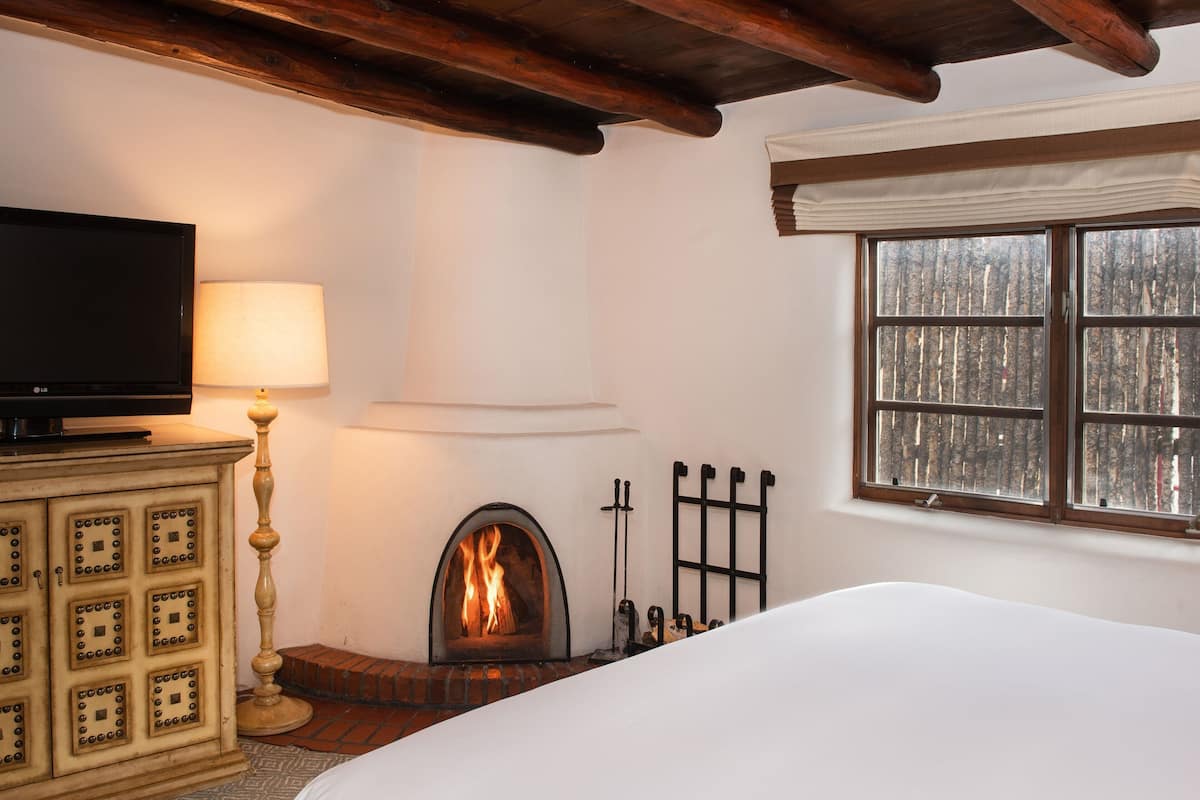 A cozy room with a fireplace, a television, and a window with a view of trees.