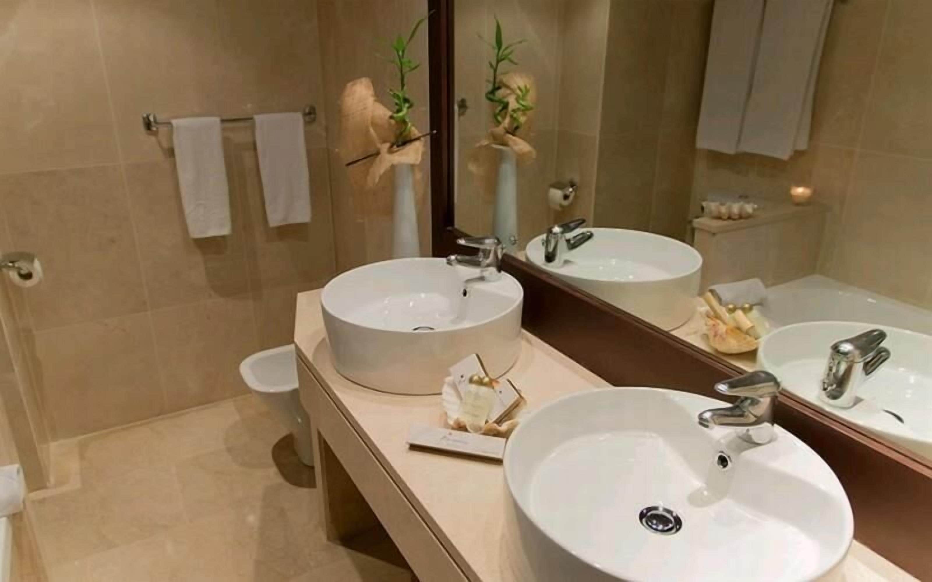Uma casa de banho moderna com duas bacias, um espelho grande e uma sanita.