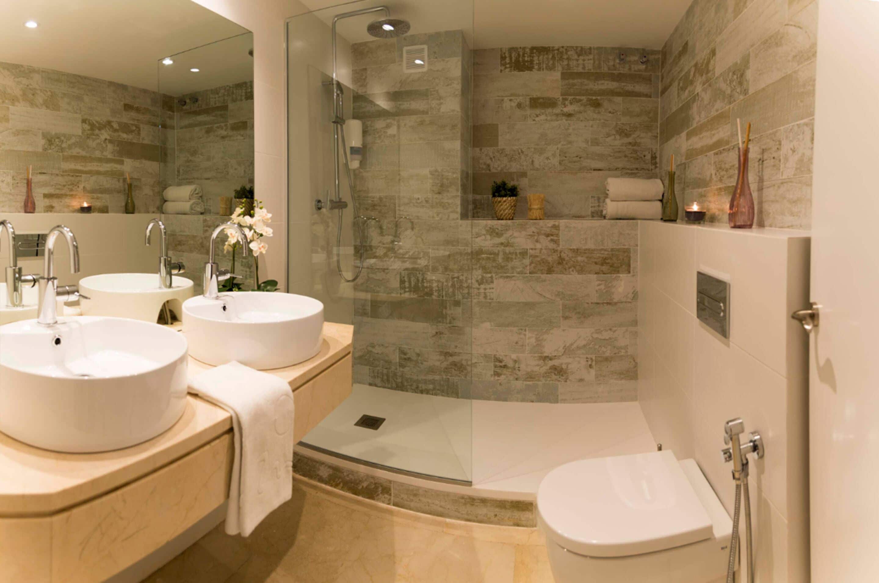 Ein modernes Badezimmer mit zwei Waschbecken, einer gläsernen Dusche und einer Toilette.