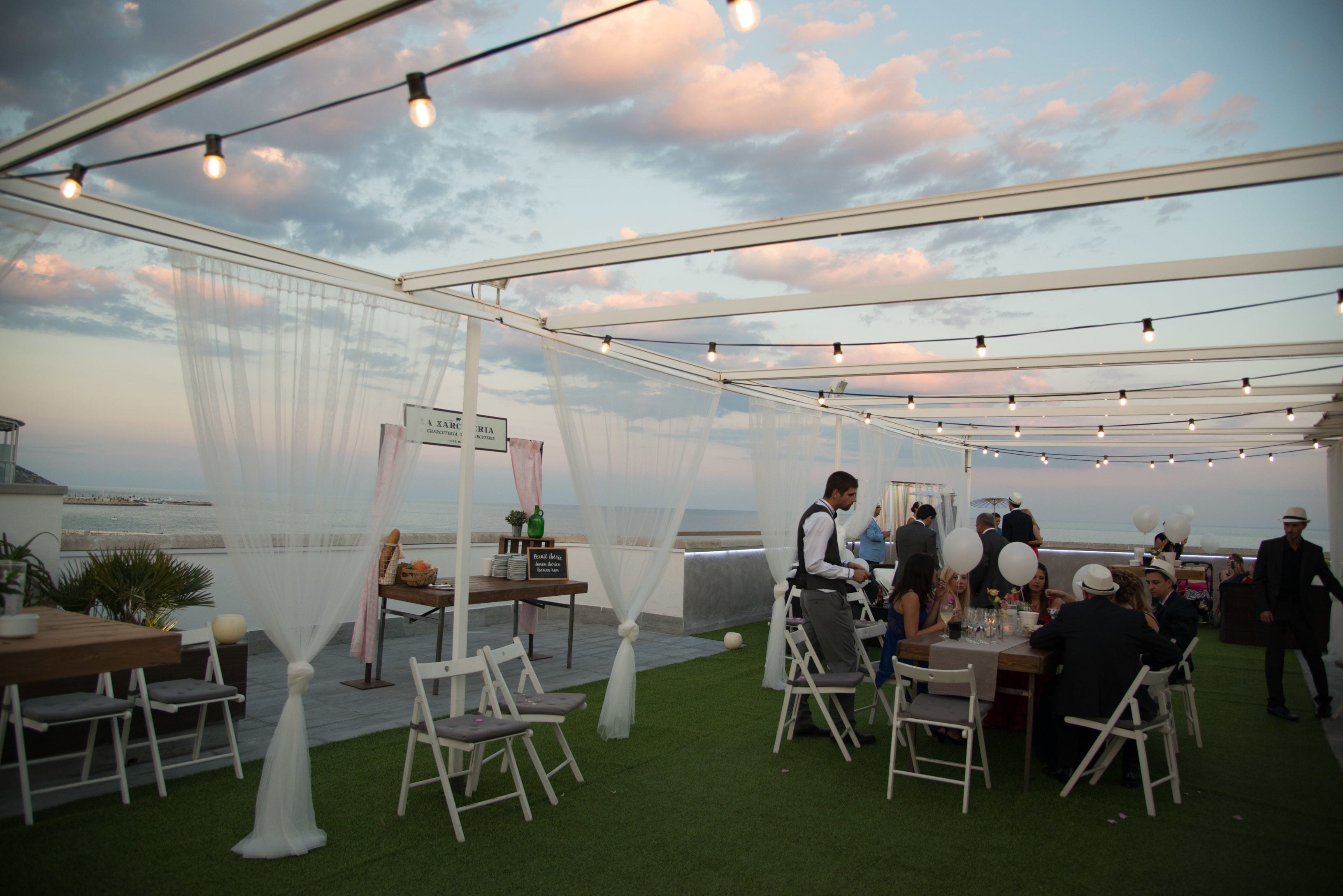 An outdoor event with tables and chairs under a tent, overlooking a body of water.