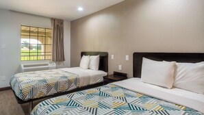 A hotel room with two beds, a window with a view, and an air conditioning unit. - Motel 6 Livingston, TX (Livingston)