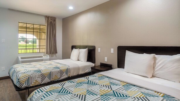 A hotel room with two beds, a window with a view, and an air conditioning unit. - Motel 6 Livingston, TX (Livingston)