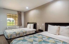 A hotel room with two beds, a window with a view, and an air conditioning unit. - Motel 6 Livingston, TX (Livingston)