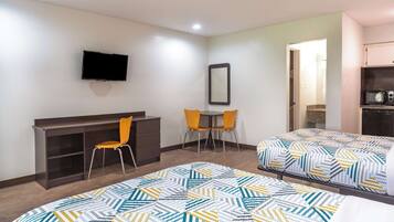 A hotel room with two beds, a desk, a chair, a TV, and a mirror.