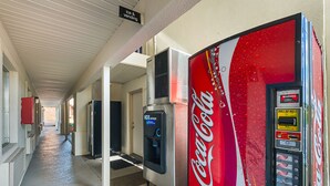 A hallway with vending machines, including a Coca-Cola machine, and a sign indicating ice and vending services. - Motel 6 Livingston, TX (Livingston)