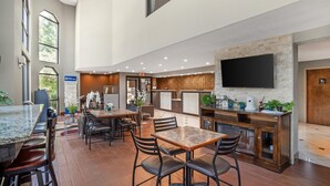 A spacious indoor area with a dining area, a kitchen counter, and a large flat-screen TV mounted on the wall. - Best Western Statesville Inn (Statesville)
