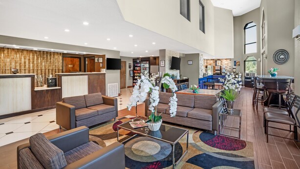A spacious hotel lobby with a reception desk, seating area, and a kitchen visible in the background. - Best Western Statesville Inn (Statesville)