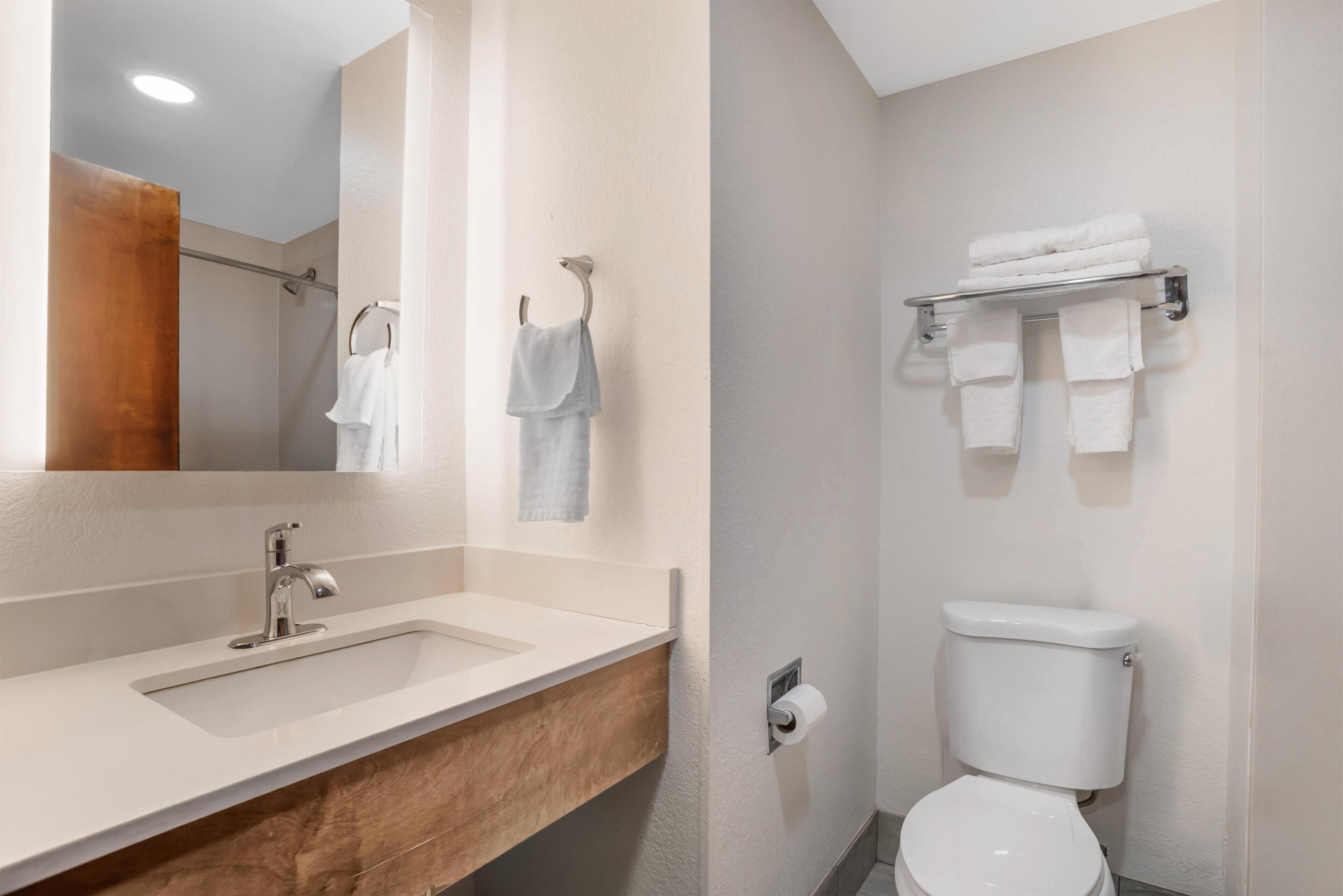 A bathroom with a sink, mirror, towel rack, and toilet.