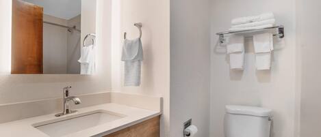 A bathroom with a sink, mirror, towel rack, and toilet.