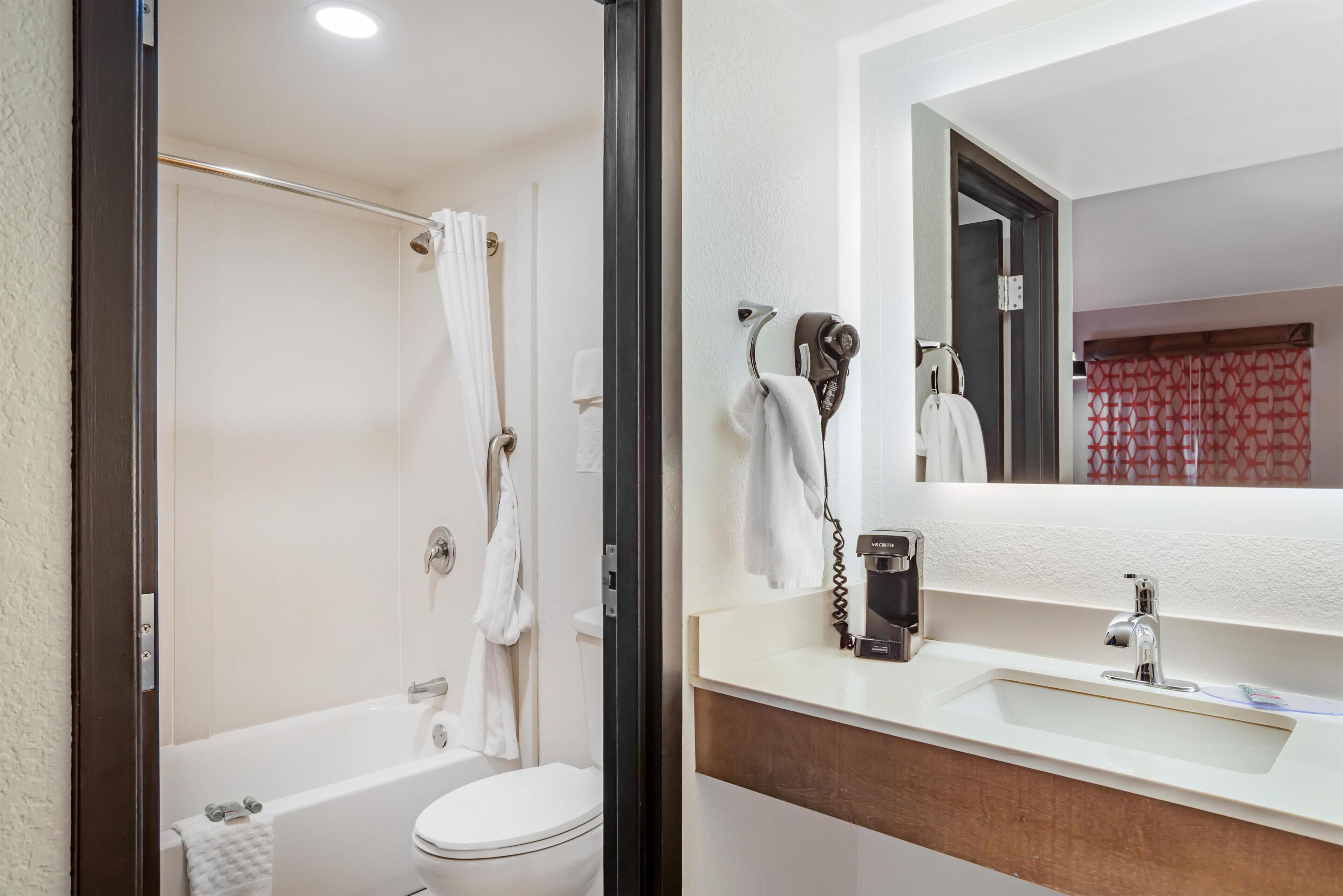 A bathroom with a bathtub, toilet, and a sink with a mirror.