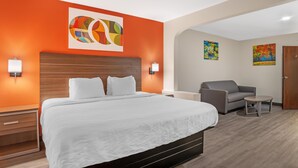 A hotel room with a large bed, a sofa, a small table, and two wall-mounted lamps. - Best Western Statesville Inn (Statesville)