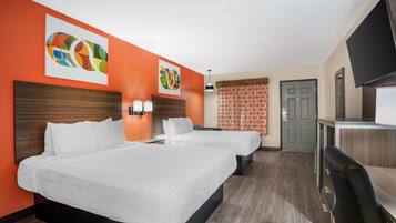 A hotel room with two beds, a desk, a TV, and artwork on the walls.