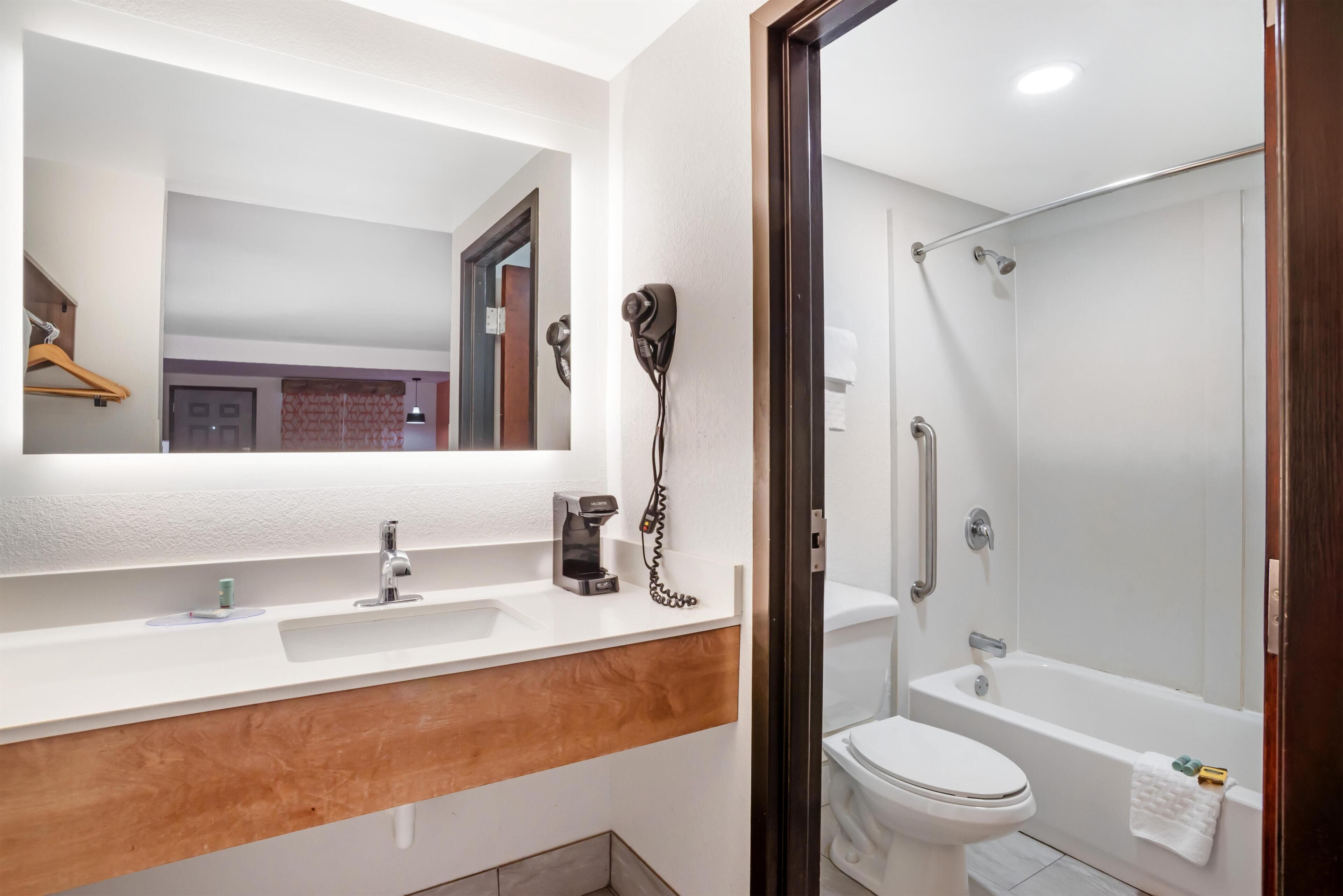 A modern bathroom with a white sink, mirror, and a walk-in shower.