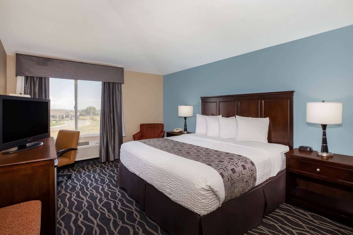 Une chambre d’hôtel avec un grand lit, une télévision, un bureau et une chaise.