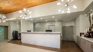 A modern reception area with a marble counter, wooden ceiling, and pendant lighting.