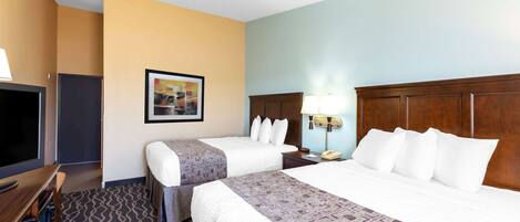 A hotel room with two beds, a TV, a desk, and a framed picture on the wall.