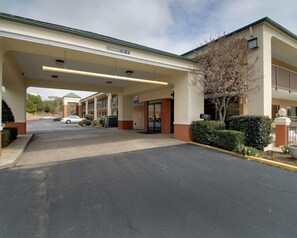 A hotel entrance with a covered parking area, a sign indicating a clearance of 10' 6", and a building with multiple balconies. - Quality Inn & Suites Clarksville (Clarksville)