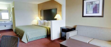A hotel room with a bed, a sofa, a desk, and a chair.