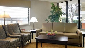 Una sala de estar con un sofá, dos sillones, una mesa de centro, una lámpara y una planta.