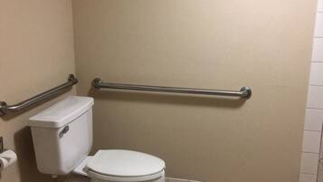 A bathroom with a toilet, grab bars, and a tiled floor.