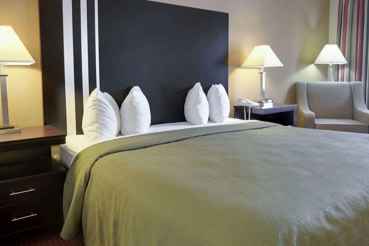 Een hotelkamer met een groot bed, twee nachtkastjes, een stoel en een hoofdbord met een zwart-wit ontwerp.