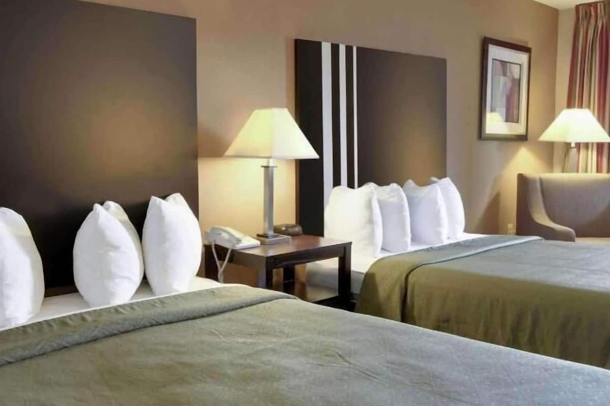 Een hotelkamer met twee bedden, een nachtkastje, een lamp en een stoel.