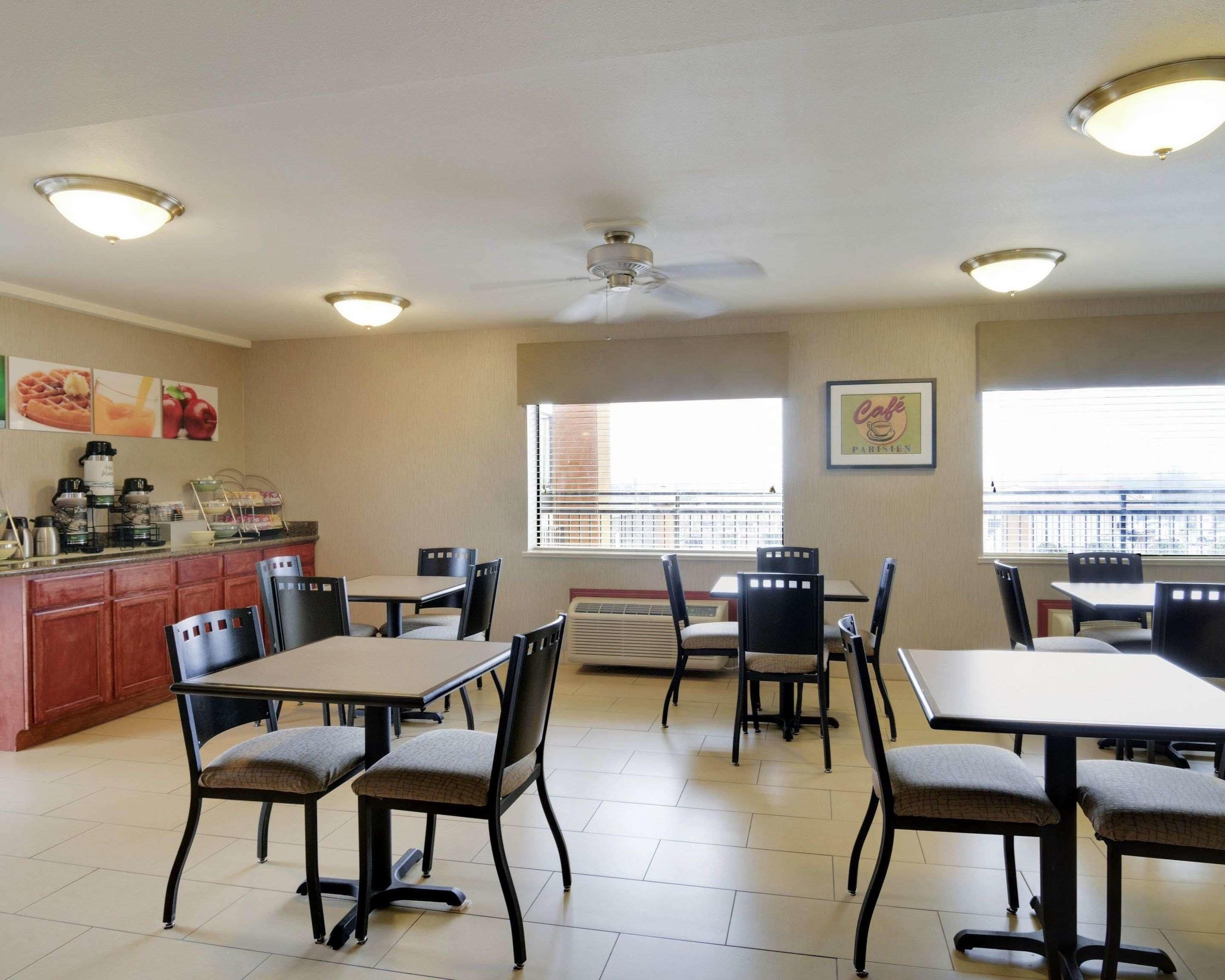 A dining area with tables and chairs, a kitchen counter with appliances, and a ceiling fan.