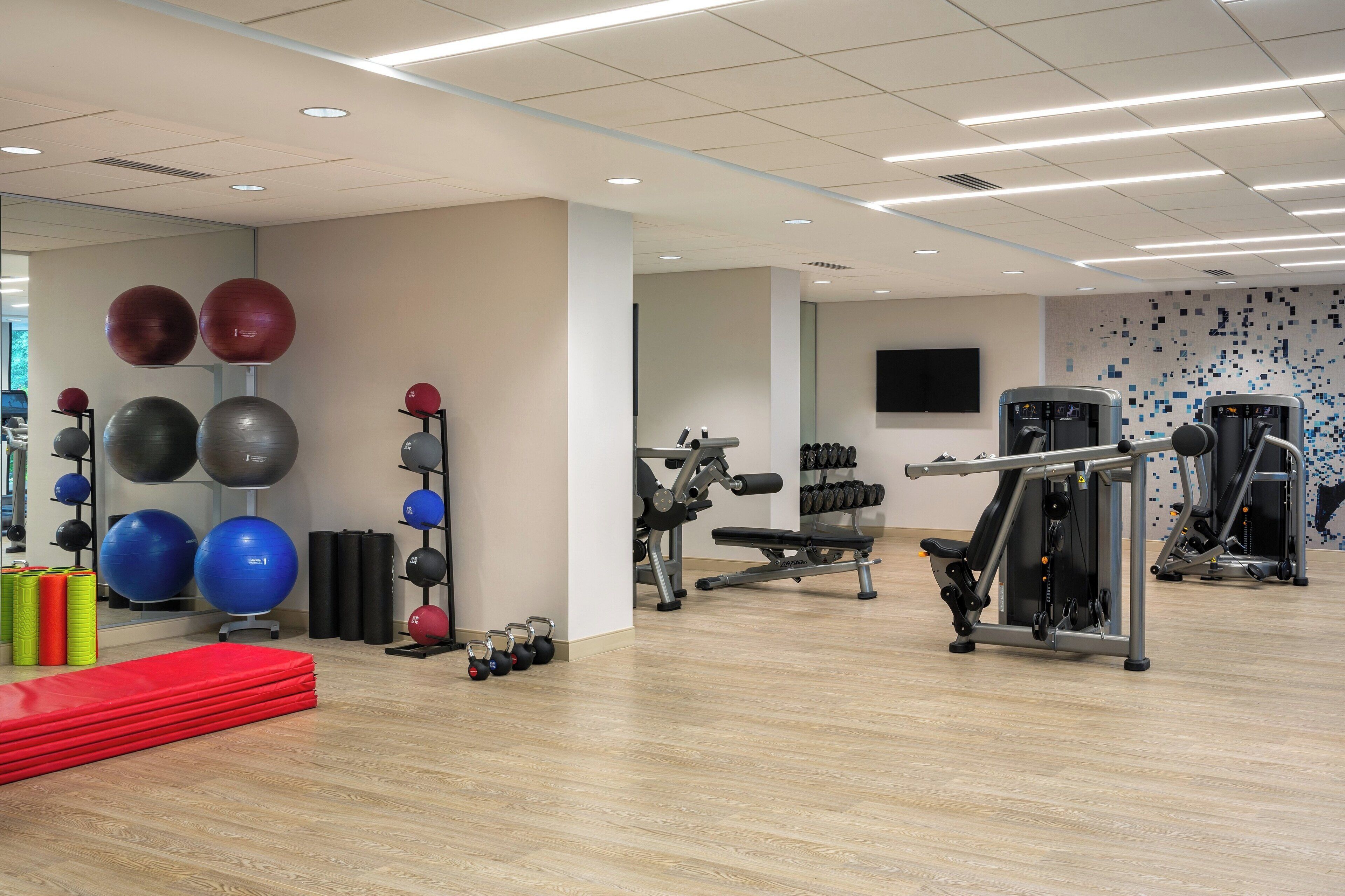 Une salle de sport équipée de ballons d’exercice, d’haltères et d’appareils de musculation.