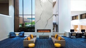 A modern lobby with a fireplace, seating area, and large windows offering a view of the outdoors. - Sheraton Norfolk Waterside Hotel (Norfolk)
