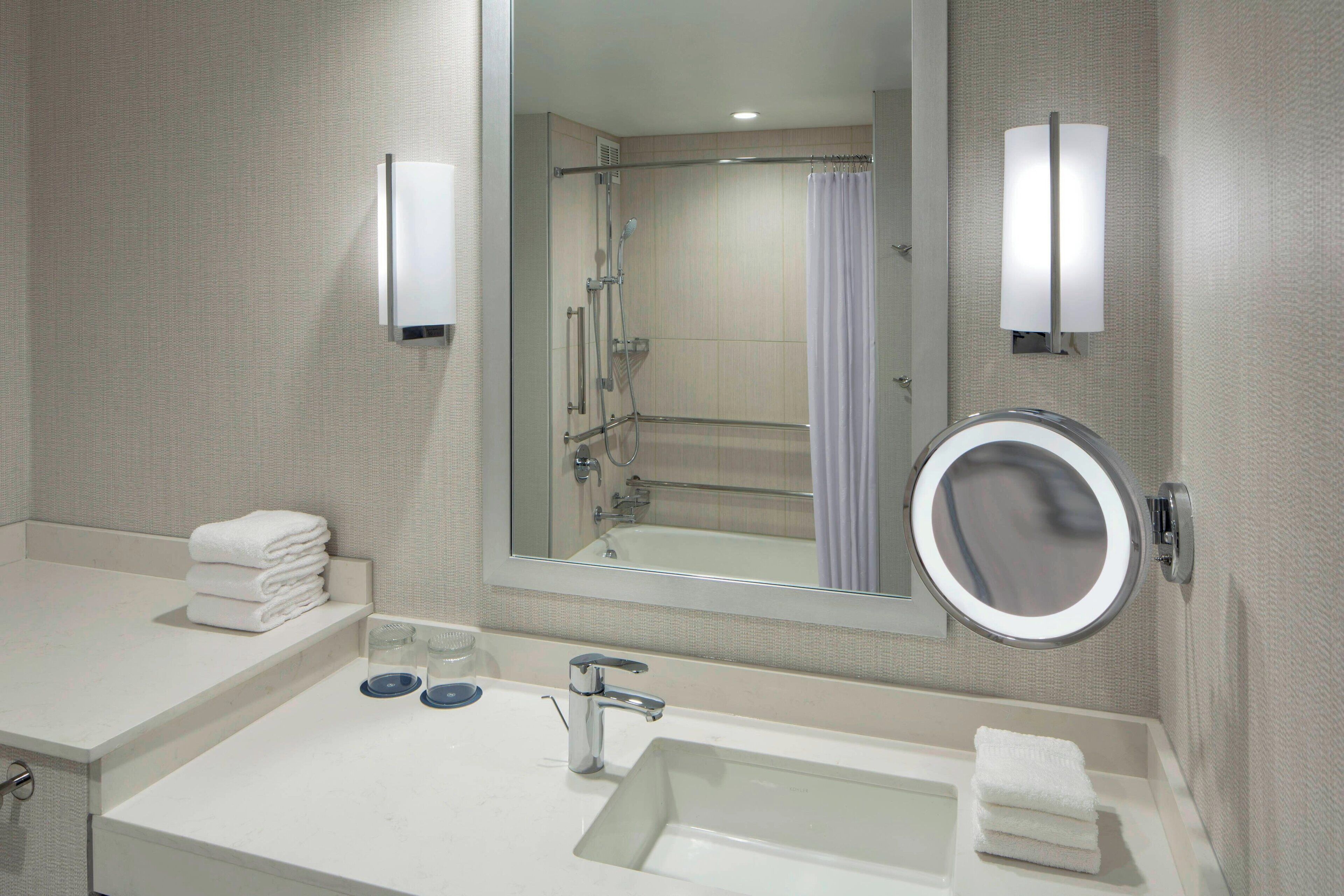 Une salle de bain moderne avec un grand miroir, un lavabo et un espace douche.