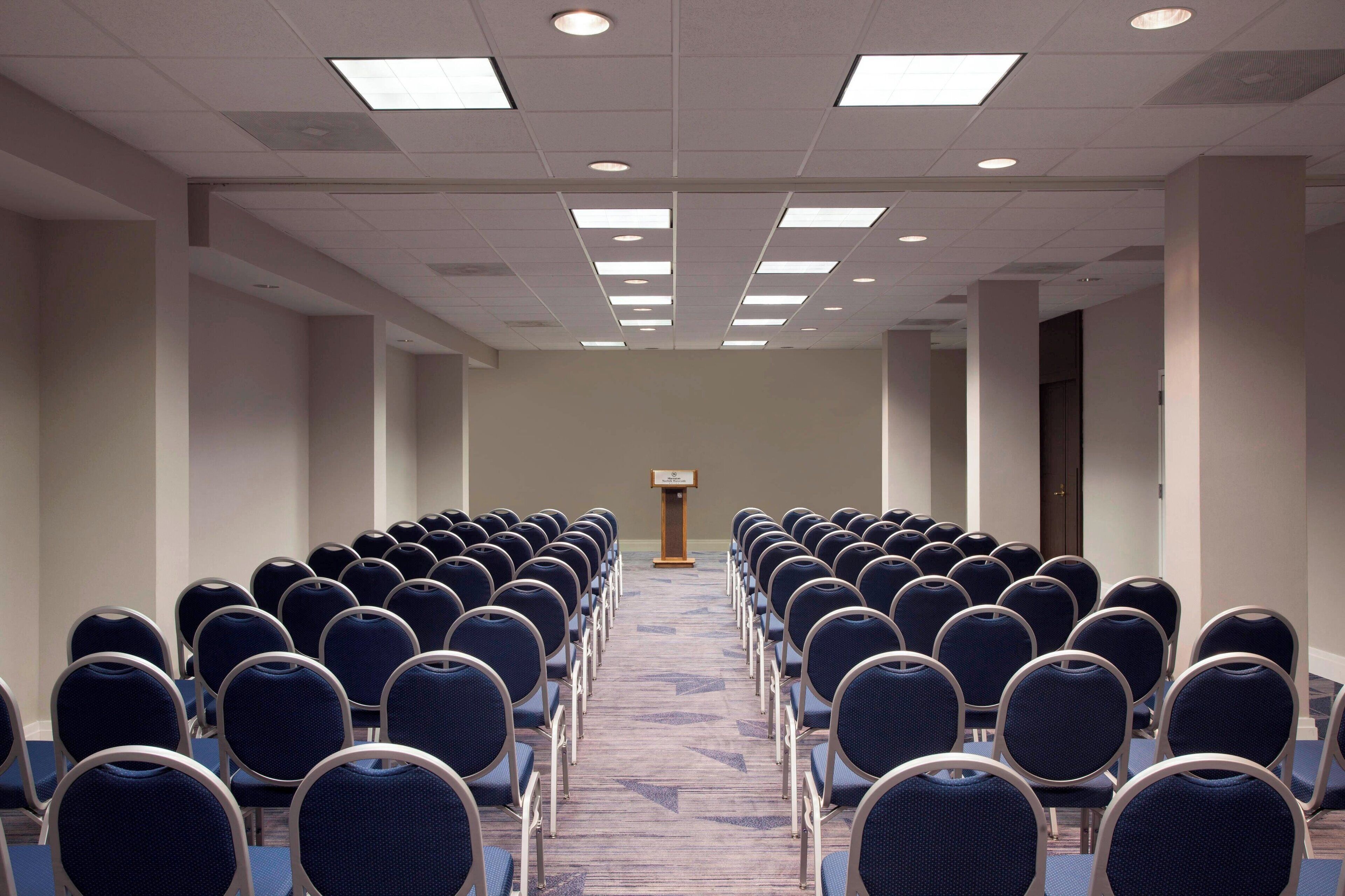 A conference room with rows of chairs facing a podium.