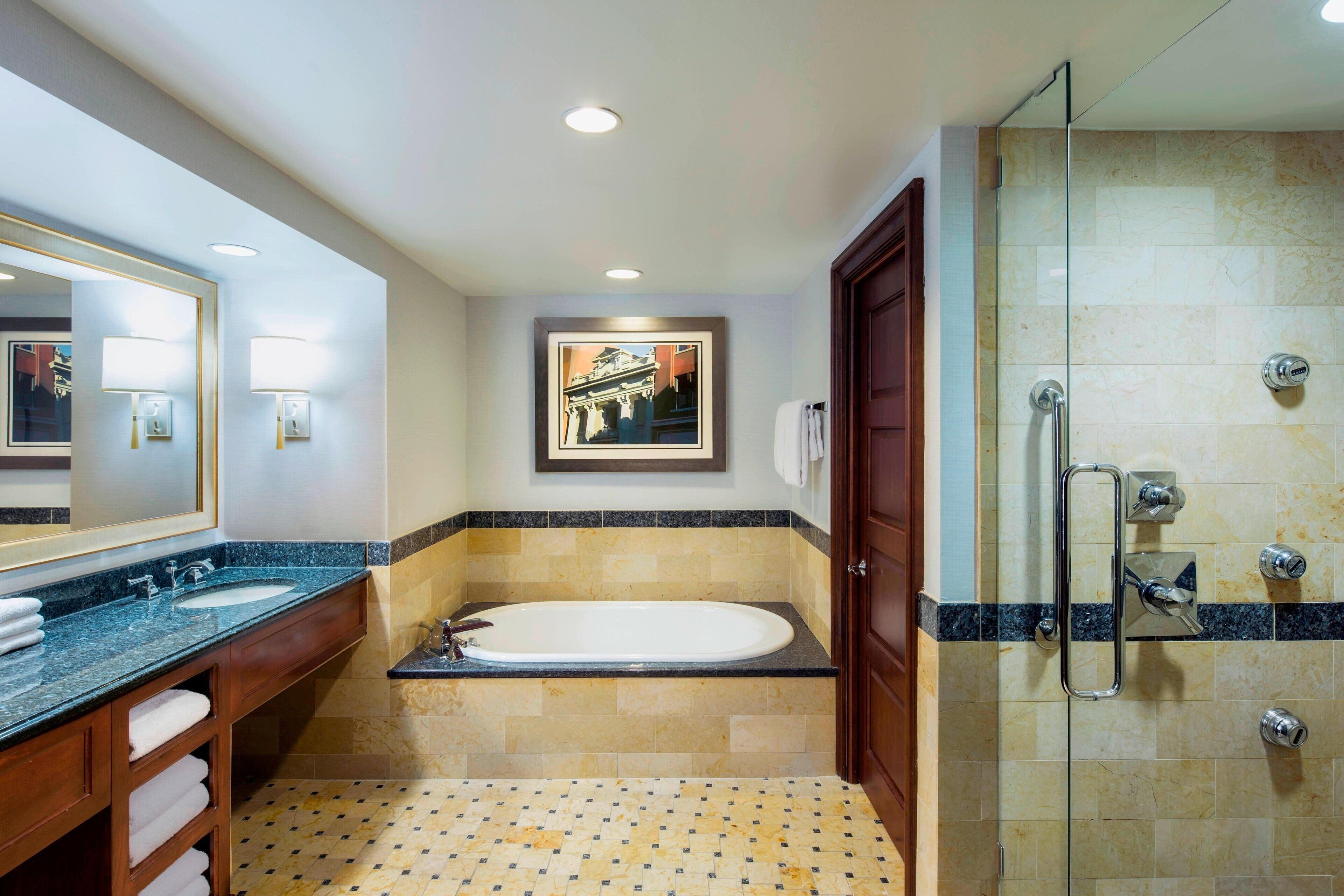 A modern bathroom with a large mirror, a bathtub, a shower, and a vanity with a sink and towel rack.